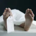 Toe Tag Hanging On Woman Lying On Table In Morgue