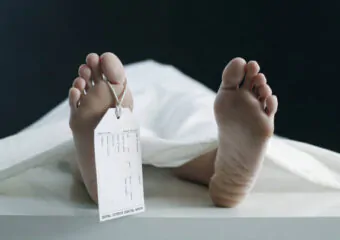 Toe Tag Hanging On Woman Lying On Table In Morgue